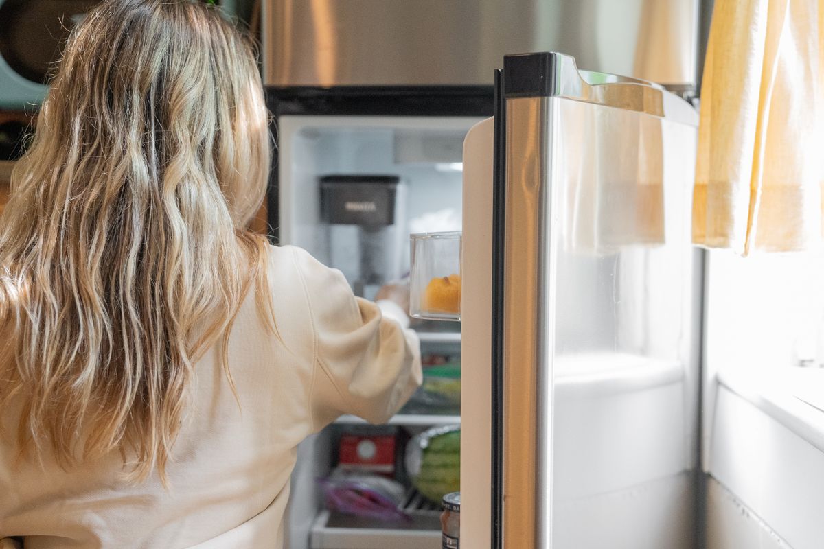 A person looking into an open fridge in a bright kitchen